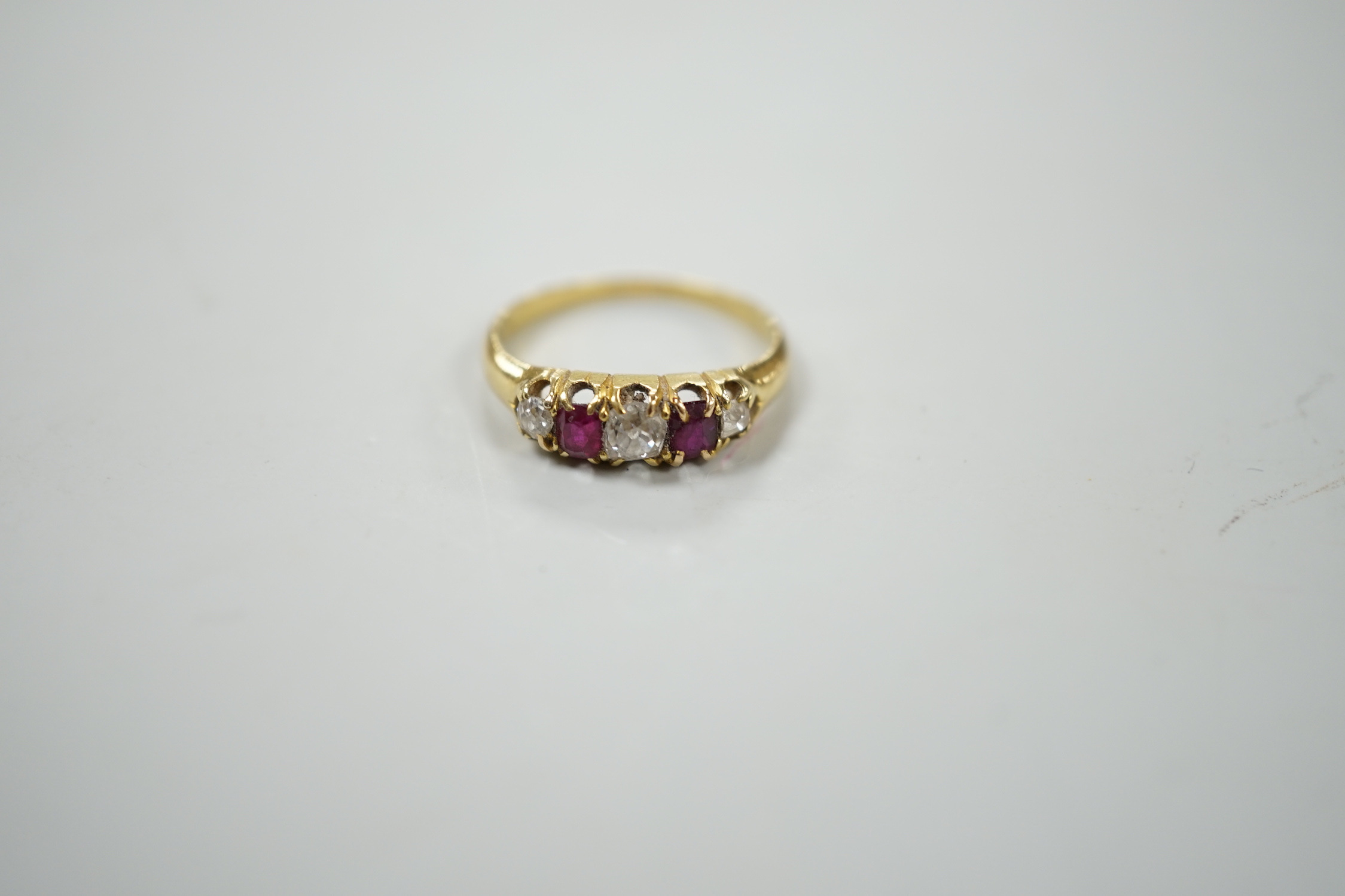 A yellow metal, two stone ruby and three stone diamond set half hoop ring, size J, gross weight 2.2 grams.